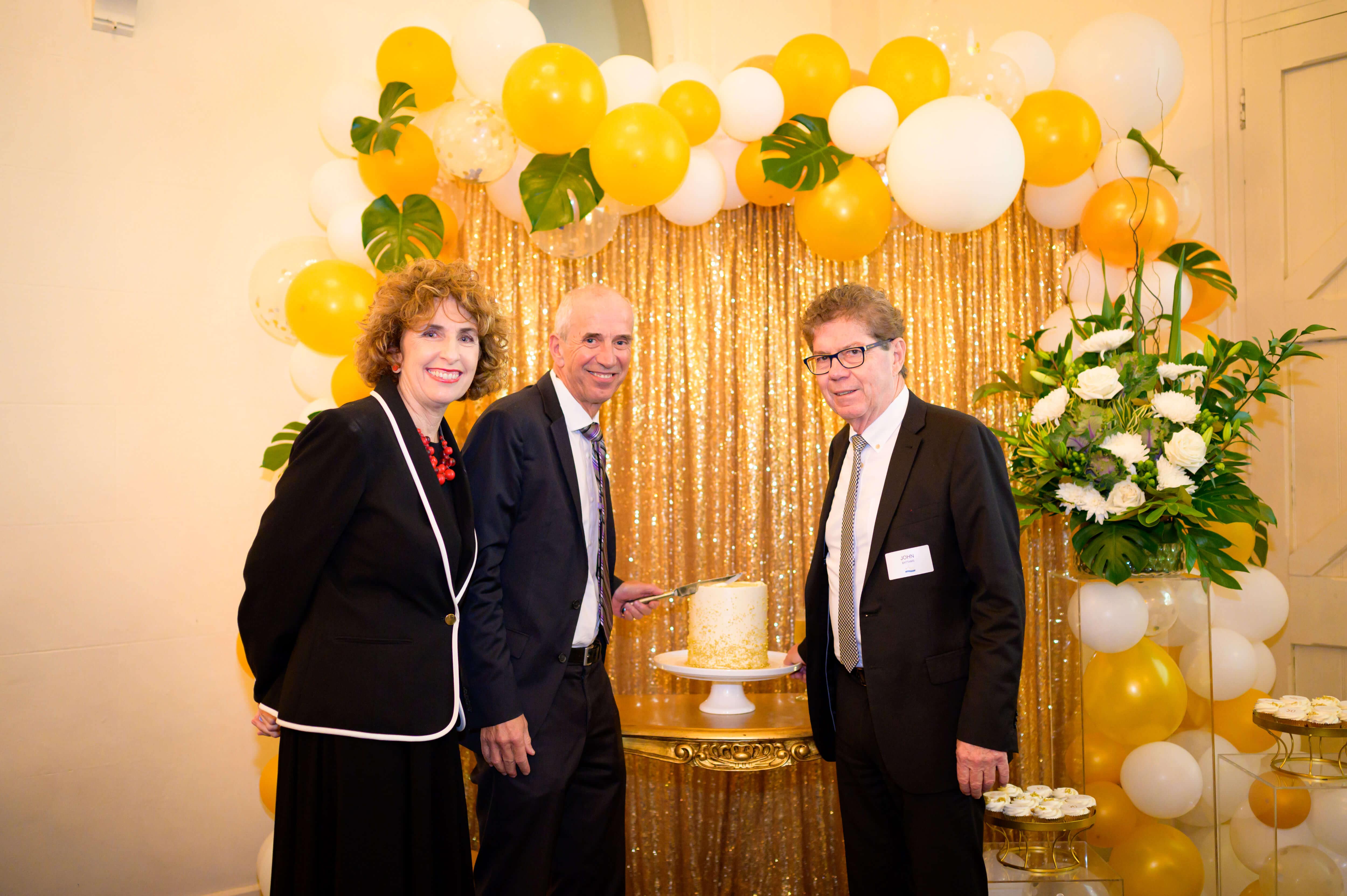 cathy mcguane, rob seljak and john battams with cake and balloons attendees at teachers union health 50th anniversary