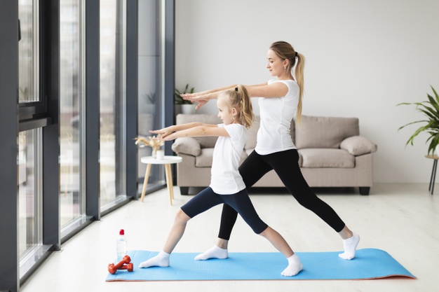 side view mother exercising along with child at home